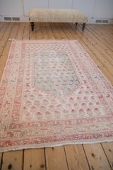 Distressed Oushak rug corner detail, featuring boteh motifs and floral border in pale raspberry, turquoise, ivory.