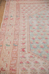 Distressed Oushak rug detail with pale turquoise boteh, raspberry floral, and worn pile.
