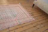 Angled view of a distressed Turkish Oushak rug with faded botanical motifs in pastel tones.