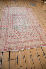 Faded pale red floral border and ivory fringe on a distressed vintage Oushak rug.