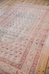 Distressed Oushak rug detail showing faded meandering vine border and pale raspberry boteh.