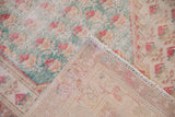 Vintage distressed Oushak rug corner, revealing faded boteh motifs and hand-knotted foundation.