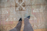 Distressed vintage Oushak rug with abrashed field, faded raspberry and seafoam tones.