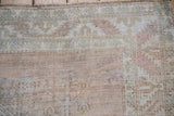 Distressed Oushak rug pile with soft raspberry, seafoam, and camel-toned patterns.