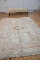 Distressed Oushak rug corner showing serrated leaf border and muted abrashed field.