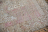 Geometric patterns and time-softened pink hues on a vintage distressed Oushak rug section.