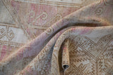 Soft pile and curvilinear motifs in pale raspberry and camel on folded Oushak rug.