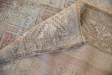 Detail of distressed Oushak rug showing angular patterns in soft beige and pale pink.