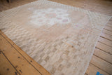 Vintage distressed Oushak carpet corner with worn checkered border and faint fuchsia spandrel.