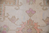 Distressed Oushak rug pile with worn fuchsia, pale cantaloupe motifs on an abrash field.