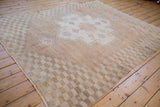 Vintage distressed Oushak rug's checkered border, abrashed field, soft faded tones.