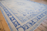 Vintage distressed Oushak carpet; ivory field, abraded pale blue floral motifs, and bold cobalt border.