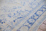 Distressed blue patterns and worn texture on an ivory vintage Oushak carpet.