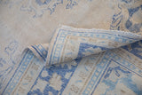 Distressed vintage Oushak rug close-up, folded border revealing cobalt blue geometric patterns and fringe.