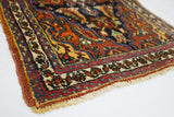 Persian Bijar rug corner, colorful primitive tribal pattern, cream floral border, and overcast edge.