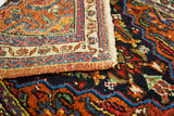 Vibrant hand-spun wool patterns in blue, orange, and red on a vintage Bijar rug corner.