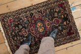 Vintage Lilihan rug mat shown for scale, with its dark floral field and time-softened texture.
