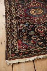 Corner detail of a vintage Lilihan rug with low pile, tattered edge, and meandering border.