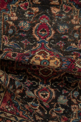 Textured close-up of the vintage Lilihan rug's floral pattern in charcoal, raspberry red, and blue.