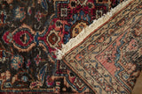 Vintage Lilihan rug corner folded to reveal the dark floral pile and the hand-knotted back.