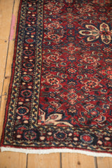 Corner of vintage Hamadan rug, showing white fringe and secured cherry red, navy border.
