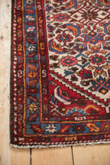 Vintage Borchalou rug's deep brown side binding, intricate red and blue borders, and off-white fringe.