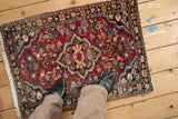 Vintage Lilihan rug corner detail with cherry red field, floral border, and ivory fringe.