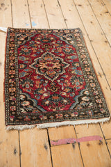 Vintage Lilihan rug corner: cherry red field with floral palmette motifs, black border, ivory fringe.