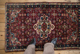 Vintage Persian Hamadan rug with a burgundy field and medallion, shown from a standing view for scale.