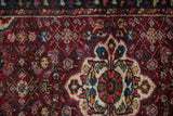 A Persian Hamadan rug's thick, hand-knotted pile featuring a scalloped medallion with floral details.