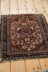 Angled view of a vintage Dargezine square rug with a dense floral pattern.