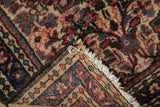The rug's corner shows the hand-knotted back, intact side cord, and dense wool pile.