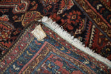 Hamadan rug folded edge, showing hand-knotted back, white fringe, and brown selvage.