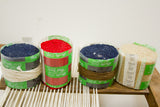 Four rolls of blue, red, and cream acrylic rug yarn on the loom's white warp threads.