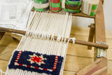 Partially woven geometric rug in navy, red, and cream on the vintage loom.