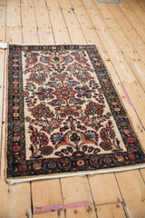 Angled perspective of a vintage Borchalou rug with a floral medallion on an ivory field.
