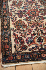 Corner detail of a vintage Borchalou rug showing floral sprays and the dark navy blue border.