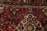 Cherry red field, colorful floral blossoms, and patterned border on a vintage Dargezine rug.