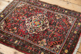 Close view of vintage Dargezine rug with cherry red floral field, dark border, and ivory fringe.