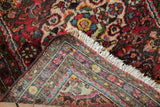 Folded vintage Dargezine rug revealing hand-knotted foundation and cherry red floral pile.