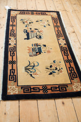 Vintage Peking rug corner with apricot border, navy key pattern, and blue-tinged fringe.