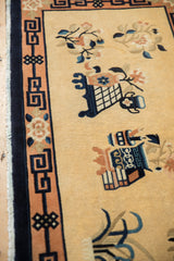 Apricot geometric border, floral motifs, and blue fringe migration on a vintage Peking rug.