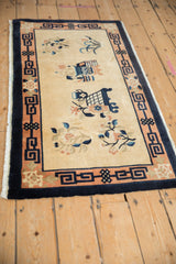 Corner of Peking rug with beige field, blue florals, apricot and navy border.