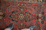 Hand-knotted floral sprays and central medallion on a dusty brick red vintage rug.