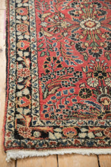 Textured low pile on the corner of a vintage Persian rug with a navy floral border and ivory fringe.