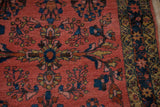 Detail of Lilihan rug's dark coral field with sapphire blue vines and gold starburst border.