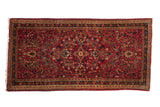 Vintage German Sarouk runner featuring a floral shadow medallion in raspberry red, navy blue, and beige.
