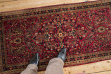 Meandering vine border and dense floral field of a vintage German Sarouk rug in red and navy hues.