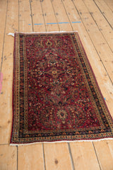 Angled view of the vintage Sarouk runner's dense floral pattern and raspberry red field.