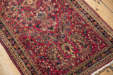 The dense, even pile of a vintage Sarouk rug in raspberry red with detailed floral motifs.